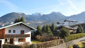 Un village de montagne aux maisons traditionnelles, avec un ciel dégagé et des sommets enneigés en toile de fond.