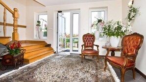 Un vaste espace de vie agrémenté d’un tapis à motifs, d’un escalier en bois et de deux fauteuils en cuir.