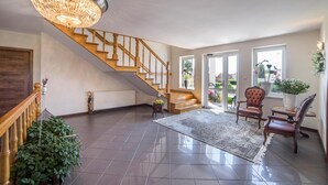 Un vaste espace de vie agrémenté d’un escalier en bois, d’un lustre et d’un grand tapis.