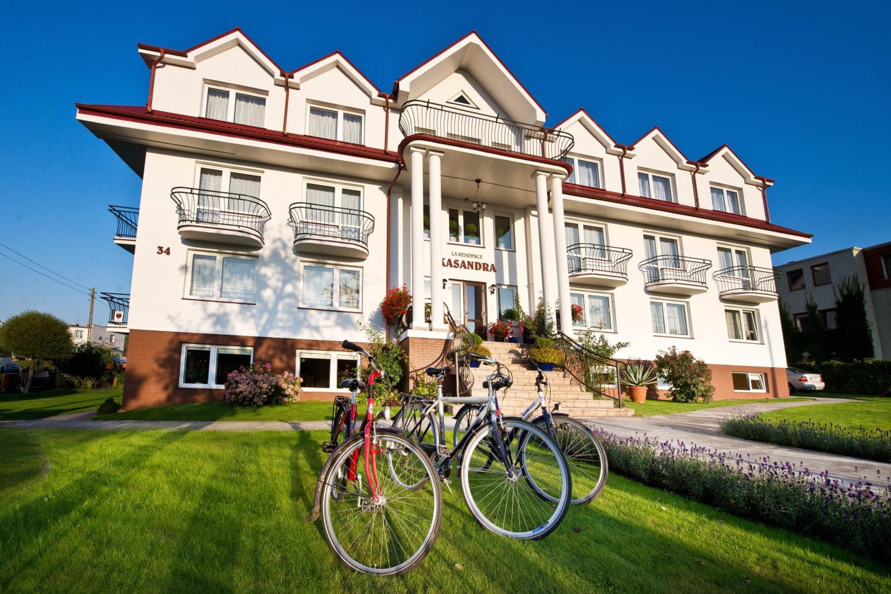Ein mehrstöckiges Hotel mit klassischer Architektur, mit Balkonen und einem gepflegten Rasen.