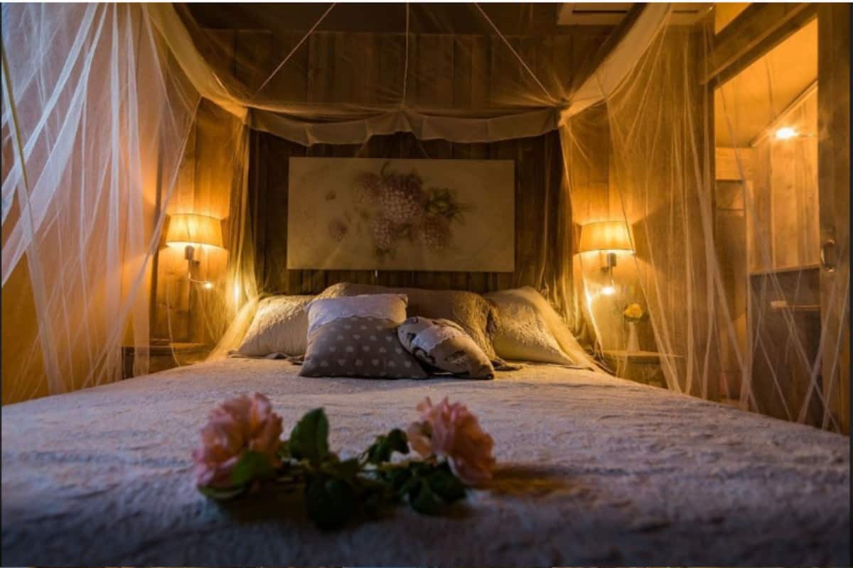 Ein Schlafzimmer mit Himmelbett, zwei Nachttischlampen und einer Blumenkomposition auf dem Bett.