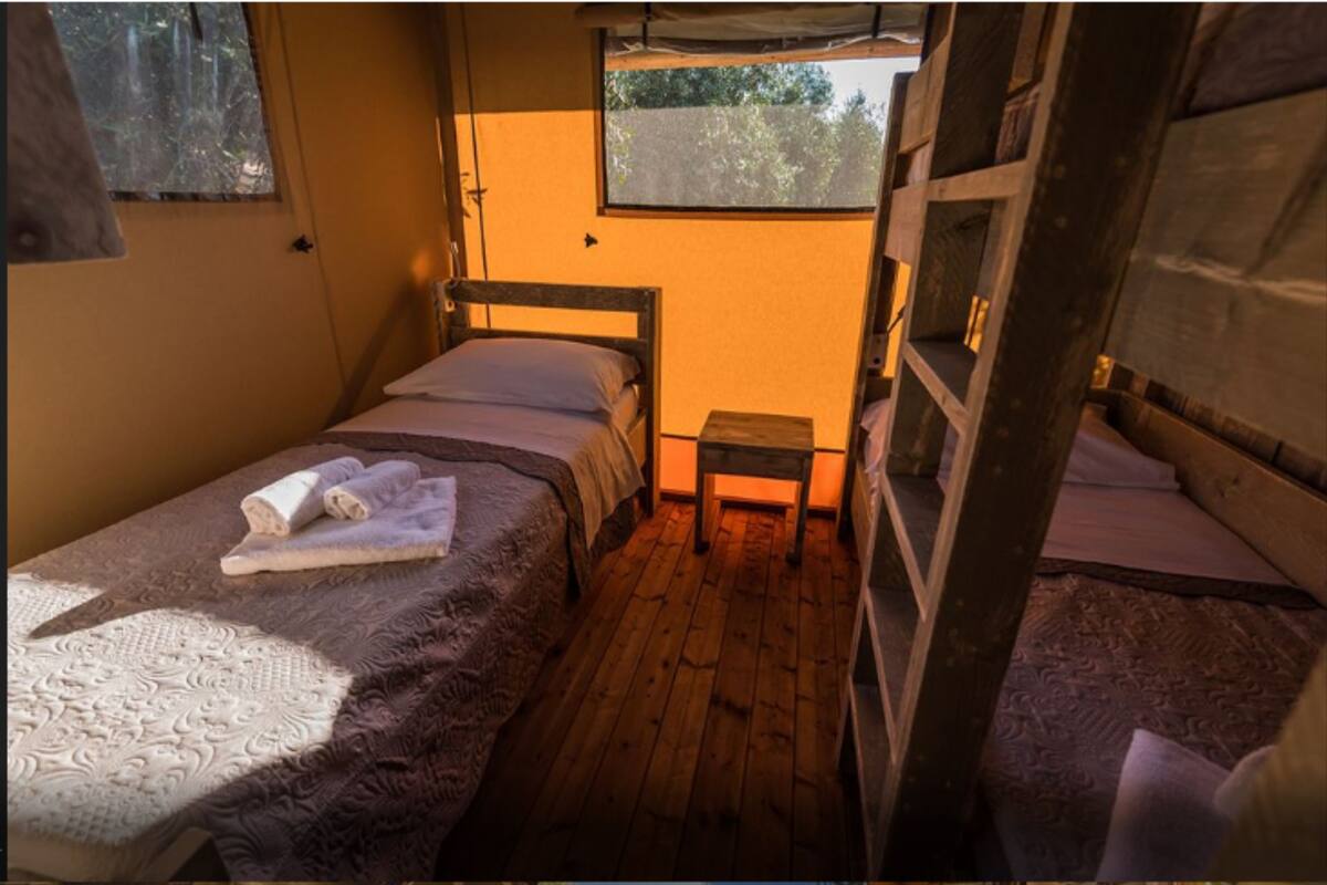 Ein kleines Zimmer mit einem Einzelbett, einem kleinen Tisch und einem Fenster.