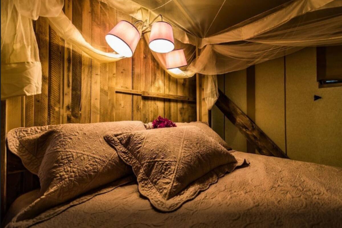 Ein Schlafzimmer mit einem Holzkopfteil, einem Bett mit einer gesteppten Decke und einer rosa Blume.