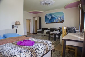 Ett hotellrum med en säng, en soffa, ett matbord och en tavla på väggen.