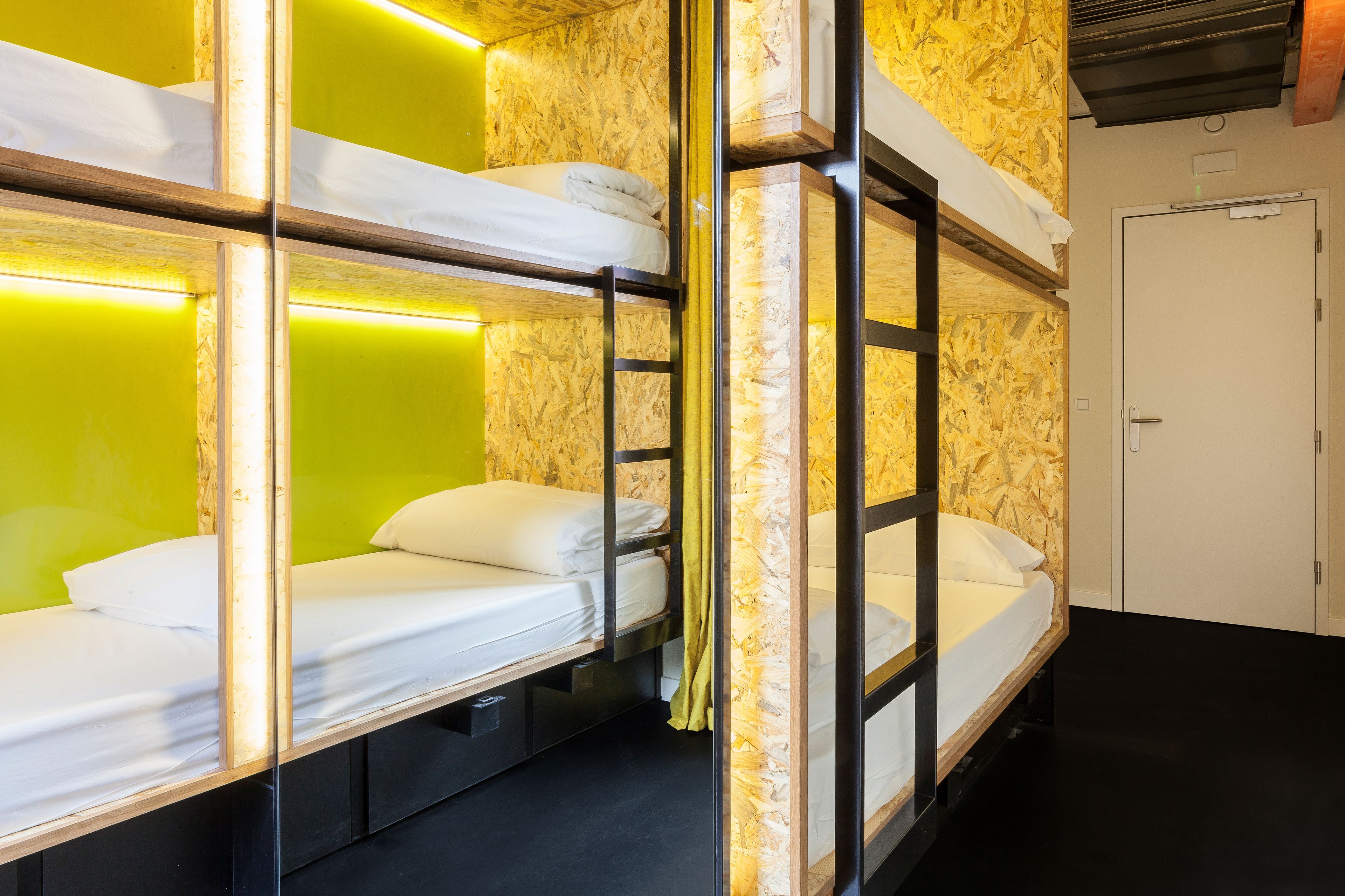 A bunk bed room with a ladder, wooden walls, and a door.