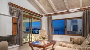 Ein Wohnzimmer mit Glastisch, beigefarbenen Sofas und Meerblick.