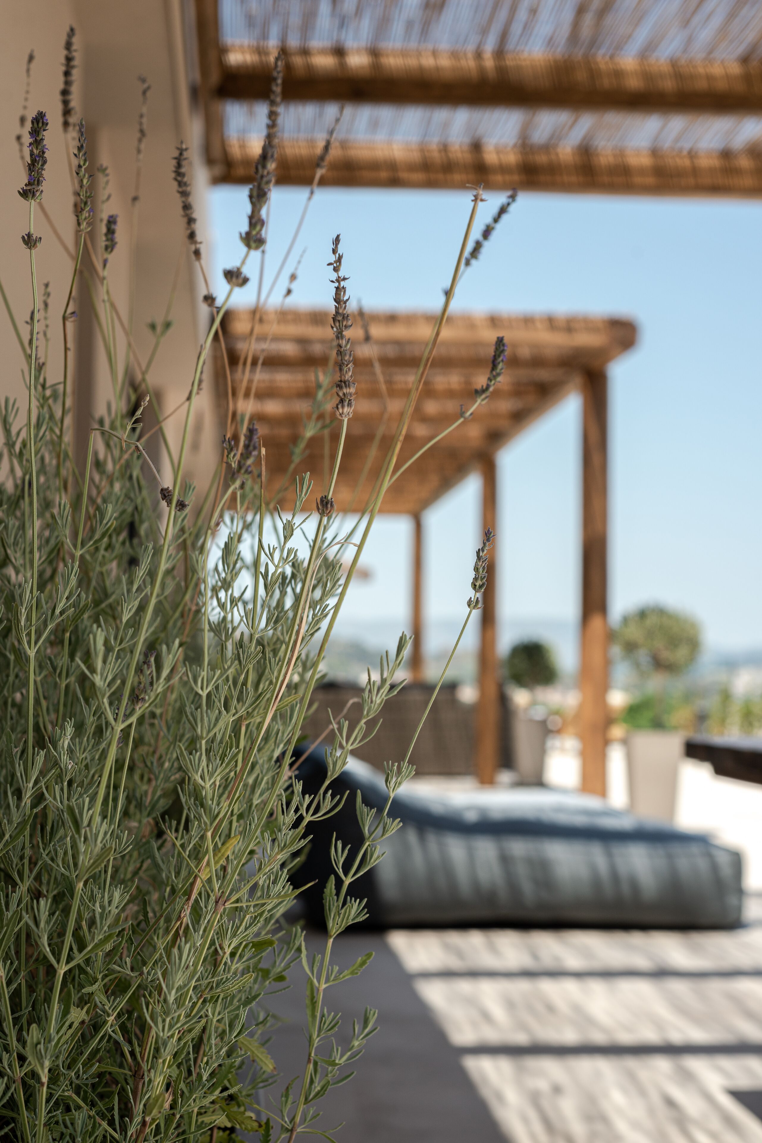 A patio area with a pergola, outdoor seating, and a view of the sea.