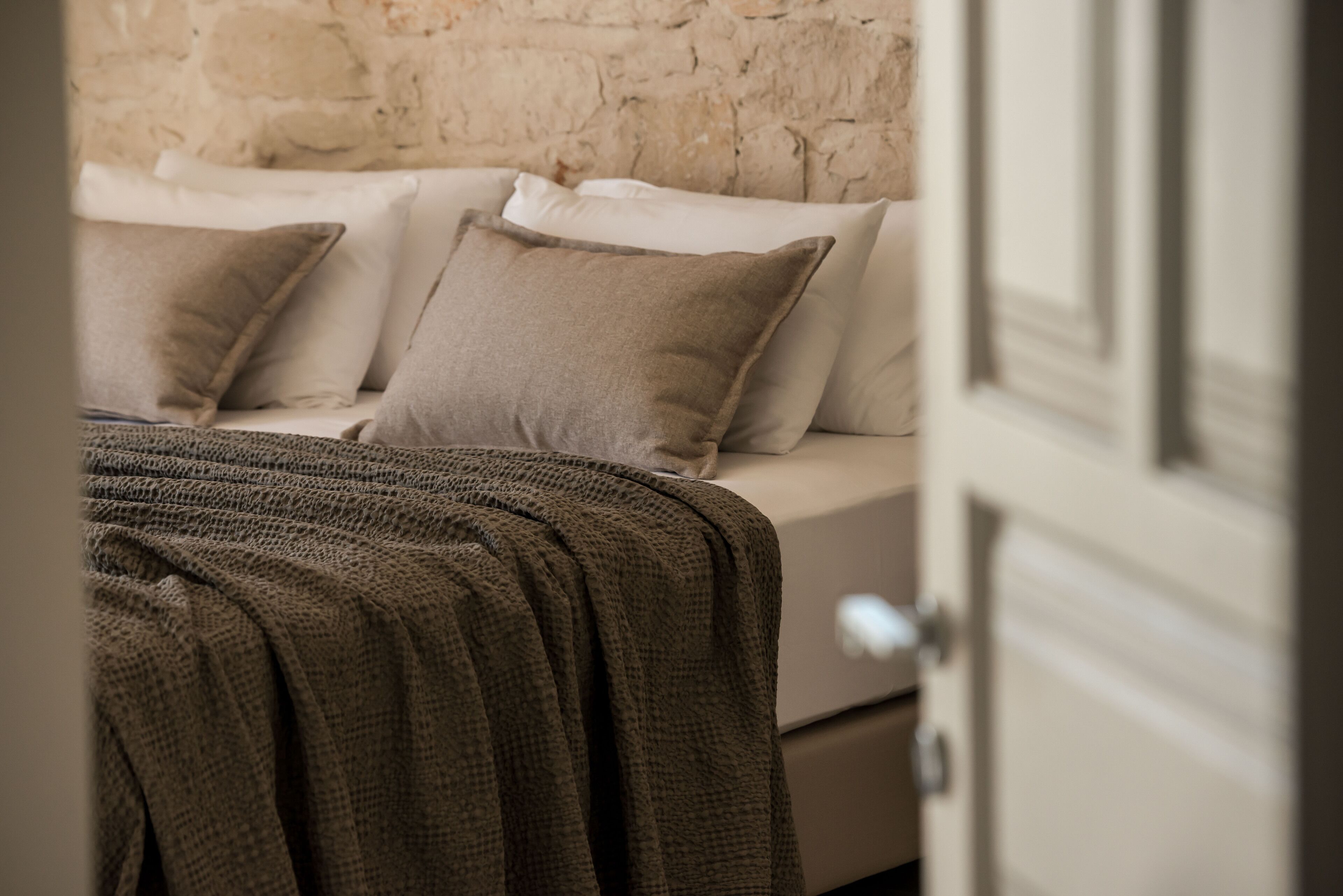 A bedroom with a bed, pillows, and a blanket.