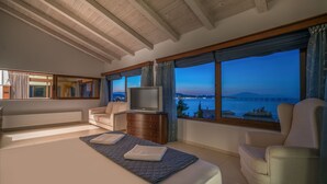 Ein geräumiges Schlafzimmer mit einem großen Bett, einem Fernseher und Meerblick.