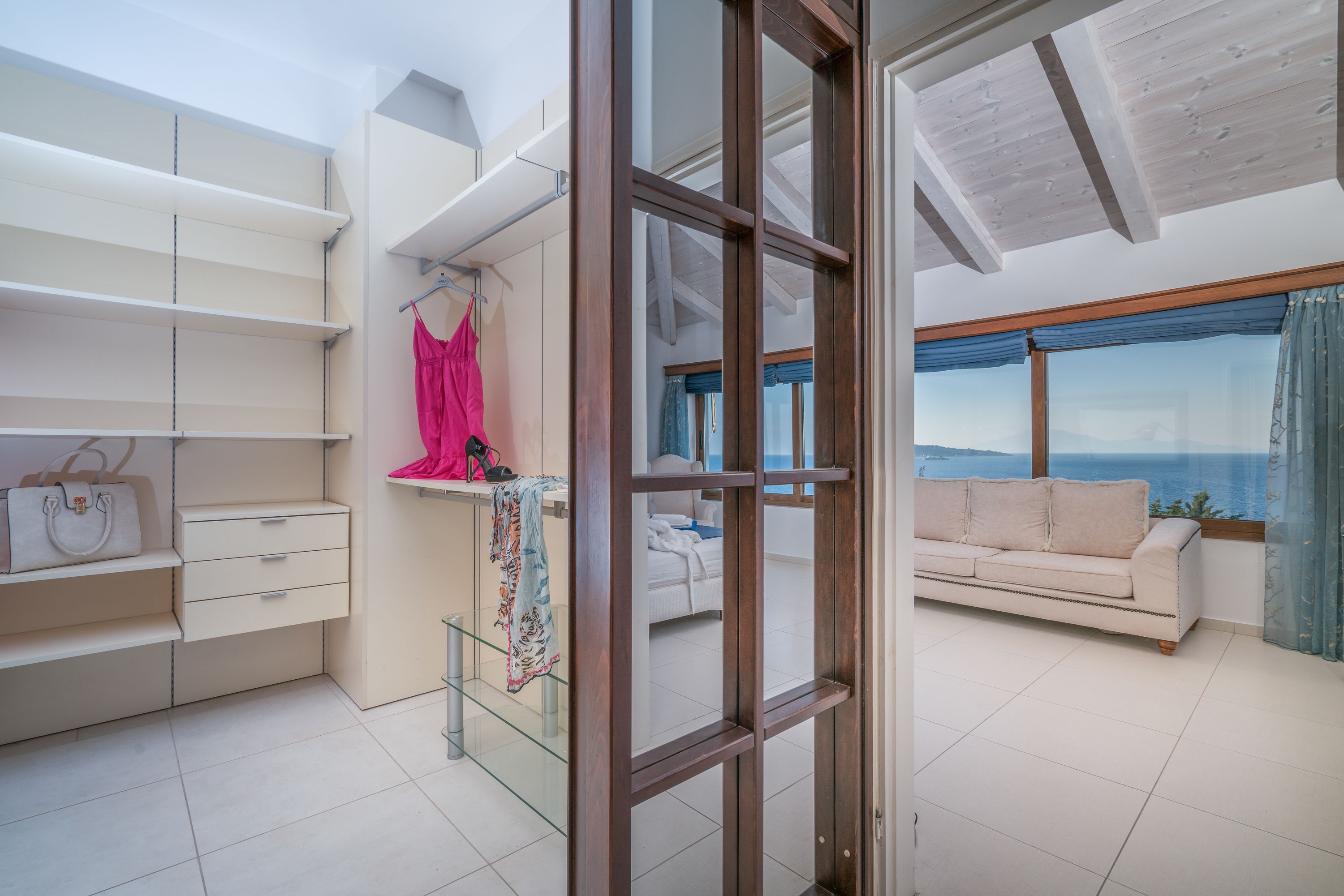 A modern room with a large window, a sofa, and a wardrobe with hanging space.