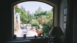 A room with a view of a garden through a window, a chair, a lamp, and a small table with a phone. - Chambres d'hôtes de Vérédème (Pujaut)