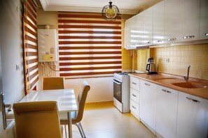 A compact kitchen with a dining table, chairs, a stove, and a sink. - Ata Apart & Hotel (Bursa)