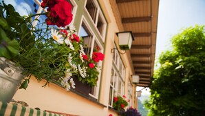 A building with flower boxes on the windows, a green-striped tablecloth, and outdoor seating. - Ostaria Posta (San Martino in Badia)
