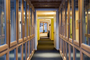 A corridor with glass doors on both sides, leading to a room with a window and a door at the end. - Ostaria Posta (San Martino in Badia)