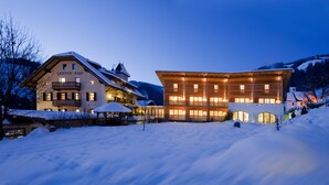 A hotel with a traditional European architectural style, featuring a snow-covered landscape and illuminated windows. - Ostaria Posta (San Martino in Badia)