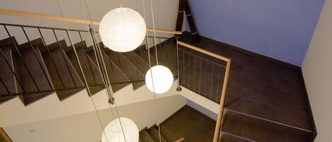 A staircase with a wooden railing and hanging spherical light fixtures.