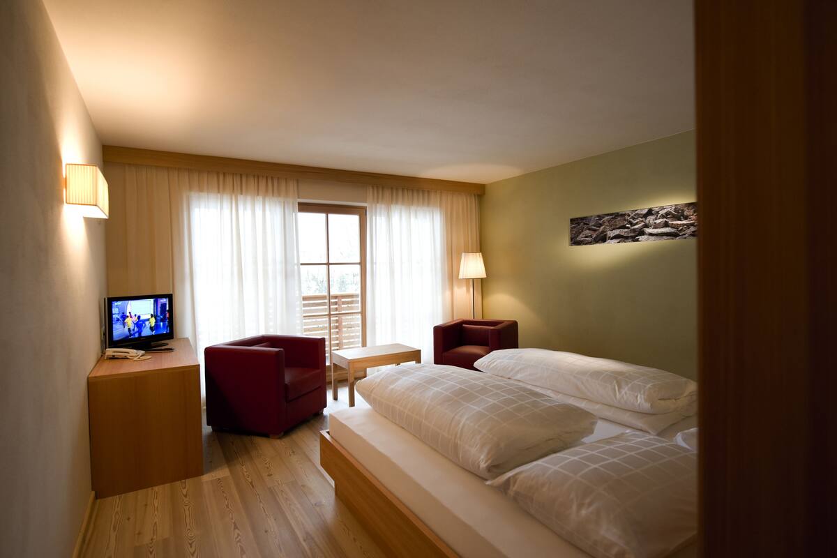 A hotel room with a bed, a TV, a desk, and a chair.