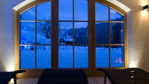 A room with a large arched window offering a snowy mountain view. - Ostaria Posta (San Martino in Badia)