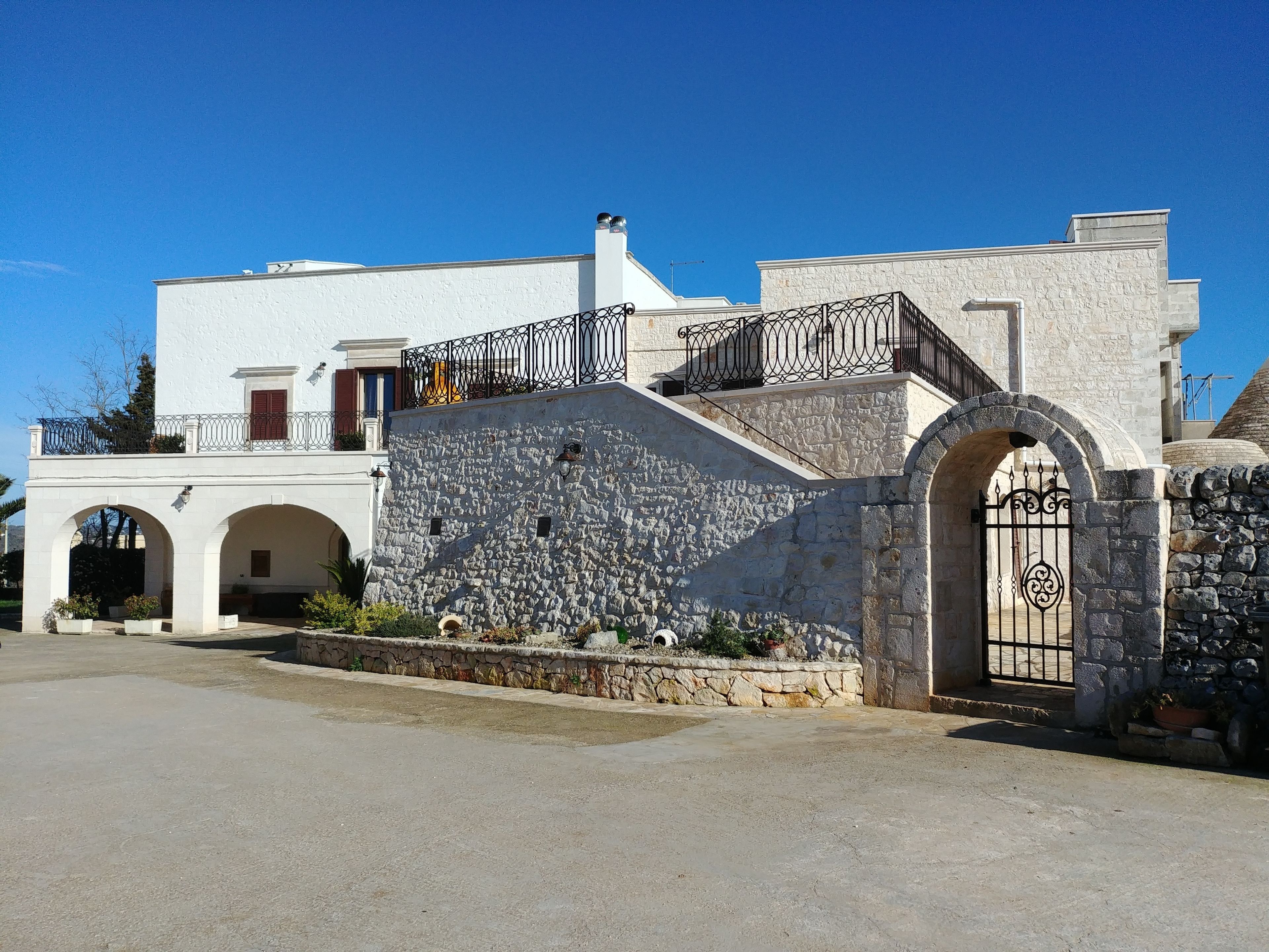 A building with a stone facade, arched entrance, and a balcony with metal railings.