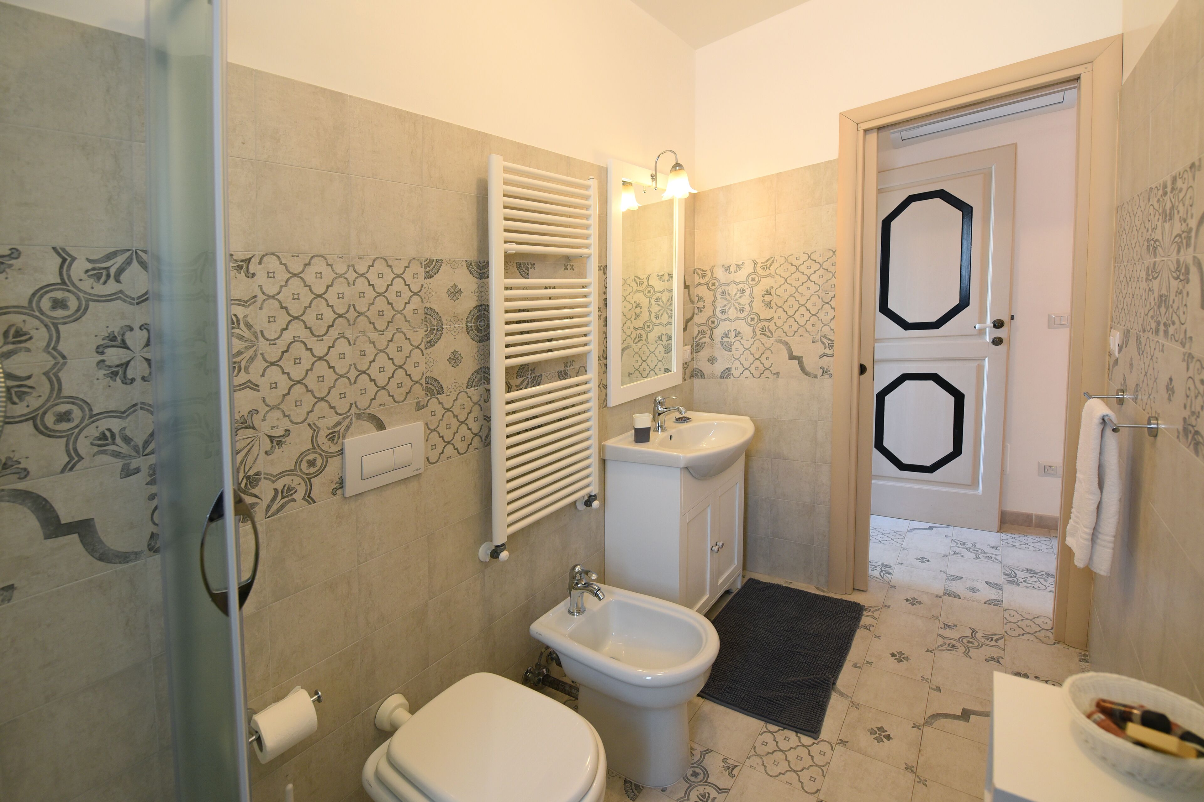 A bathroom with a toilet, bidet, sink, and towel rack.