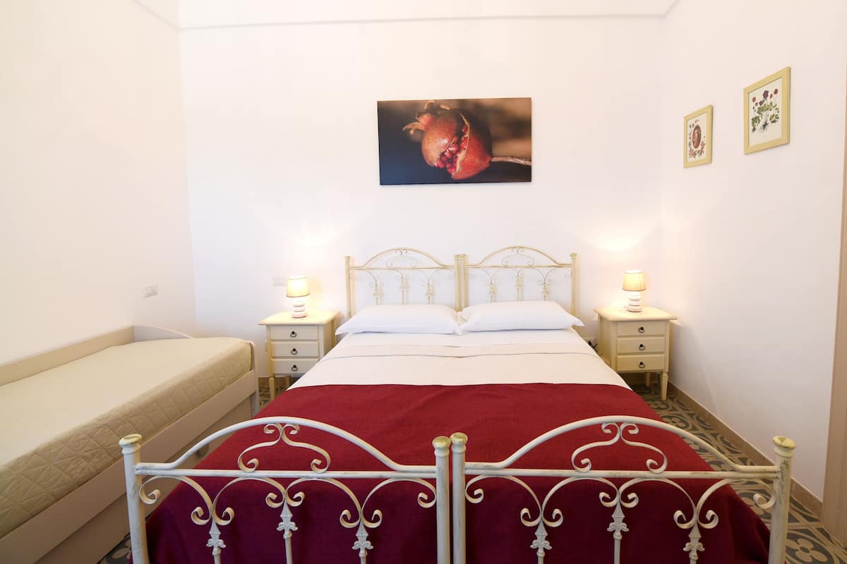 A bedroom with a bed, bedside tables, a bench, and wall art.
