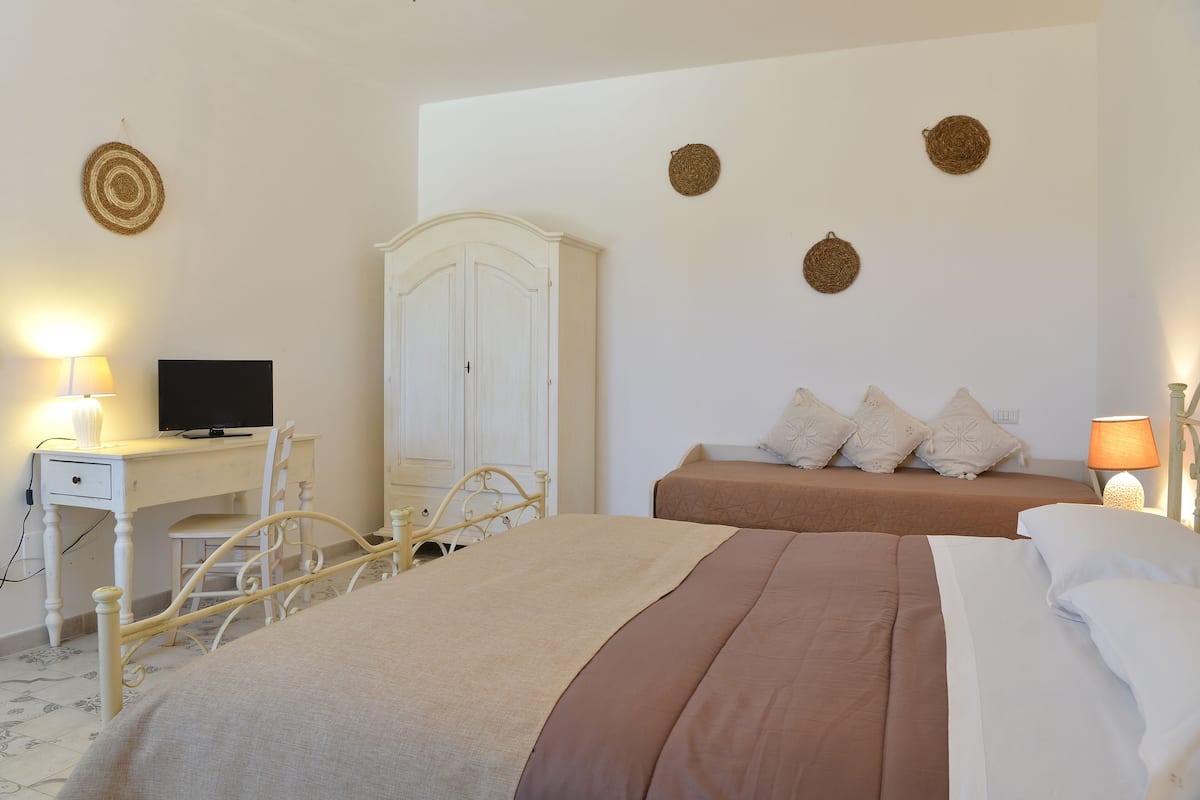 A bedroom with a bed, a desk, a chair, a wardrobe, and wall decorations.