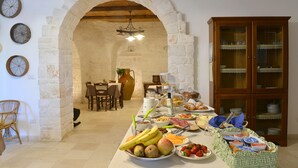 A breakfast buffet with various food items and a stone archway leading to a dining area. - Masseria Peppeturro (Cisternino)