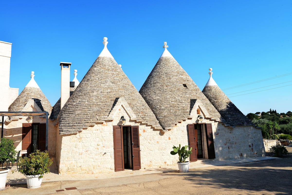 A row of stone buildings with conical roofs and wooden shutters.