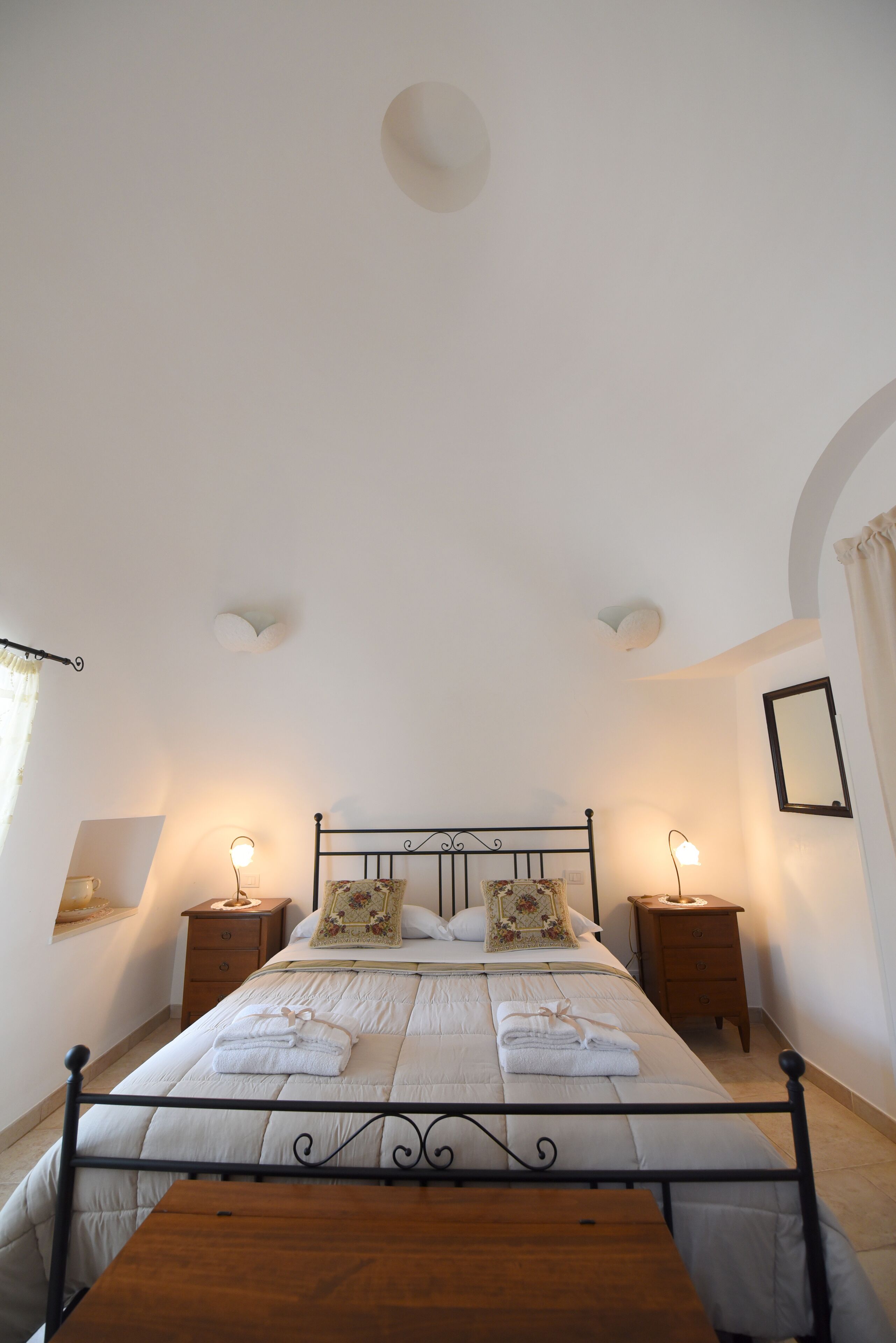 A neatly arranged bedroom with a bed, bedside tables, and a wooden table.