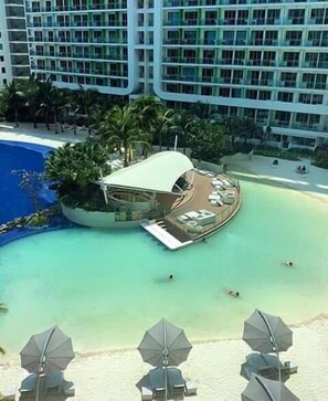 A resort with a pool, lounge chairs, and umbrellas. - Maui 2 Bedroom Condo at Azure Urban Resort Residences (Parañaque)