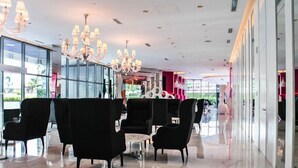 A modern lobby with black seating, chandeliers, and large windows. - Maui 2 Bedroom Condo at Azure Urban Resort Residences (Parañaque)