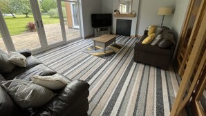 A living room with a sofa, a coffee table, a TV, and a fireplace. - Haymills Guesthouse (Solihull)