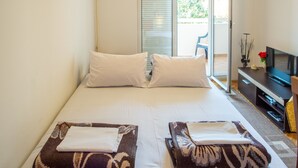 Habitación de hotel con una cama grande, dos almohadas, un televisor y un balcón.