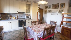 A kitchen with white cabinets, a dining table with chairs, and a hanging light fixture.