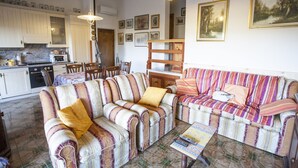 A cozy living room with striped sofas, a coffee table, and a dining area with chairs and a table.
