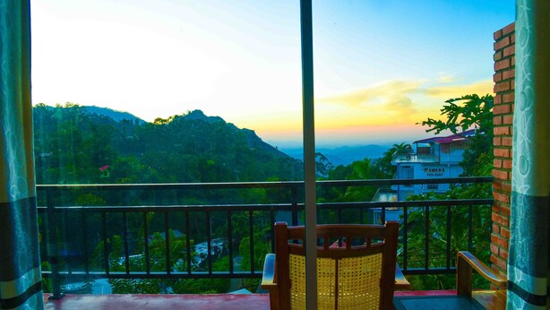 Un balcon offrant une vue sur un paysage montagneux et un bâtiment portant l’inscription « RAWANA HOLIDAY ».