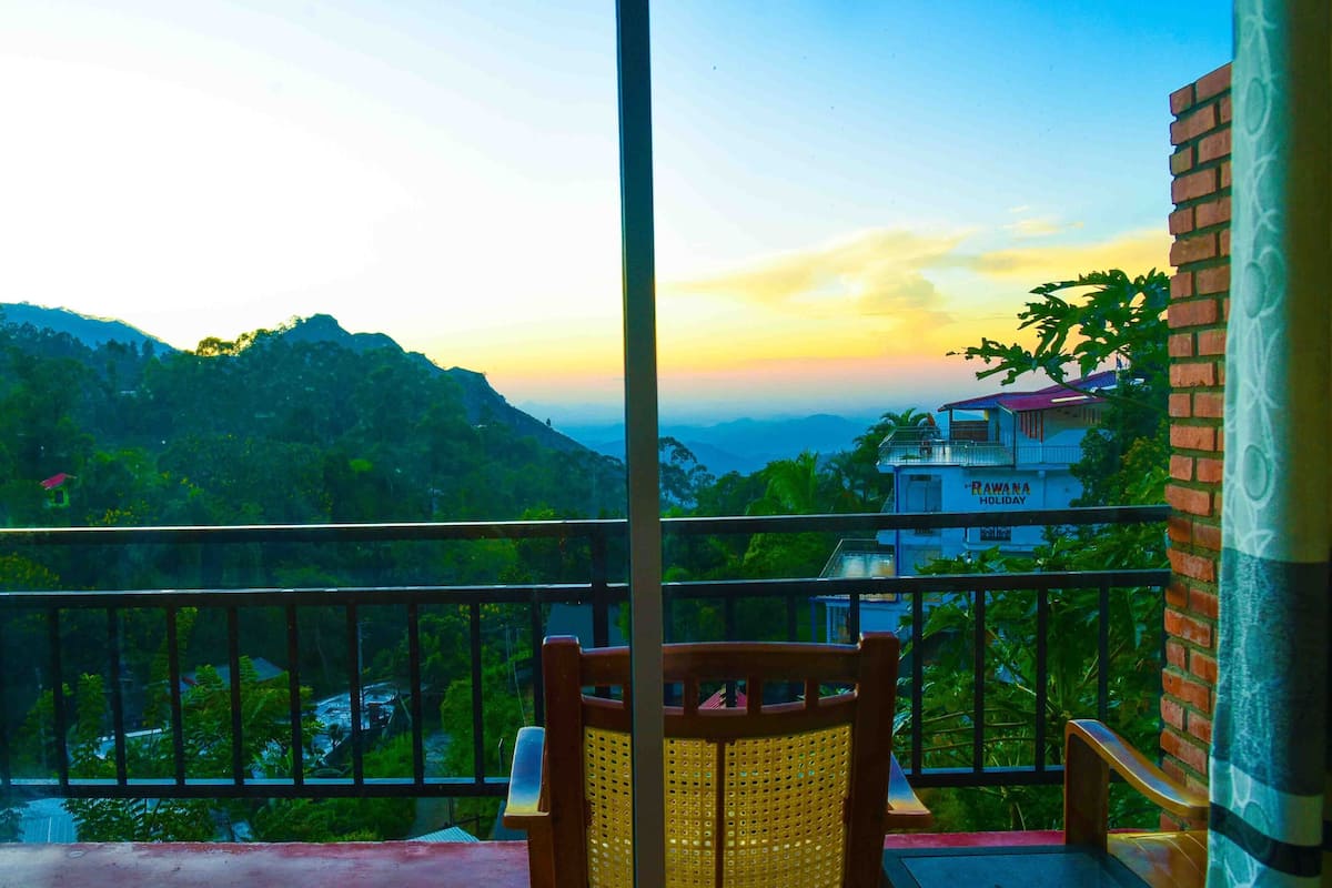 A balcony with a view of a mountainous landscape and a building labeled "RAWANA HOLIDAY".