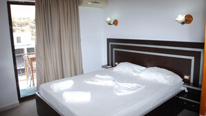 A hotel room with a bed, a nightstand, a lamp, and a window with curtains. - Hotel Freskia (Sarandë)