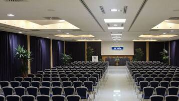 A conference room with rows of chairs, a stage, and a 'le sale' sign.