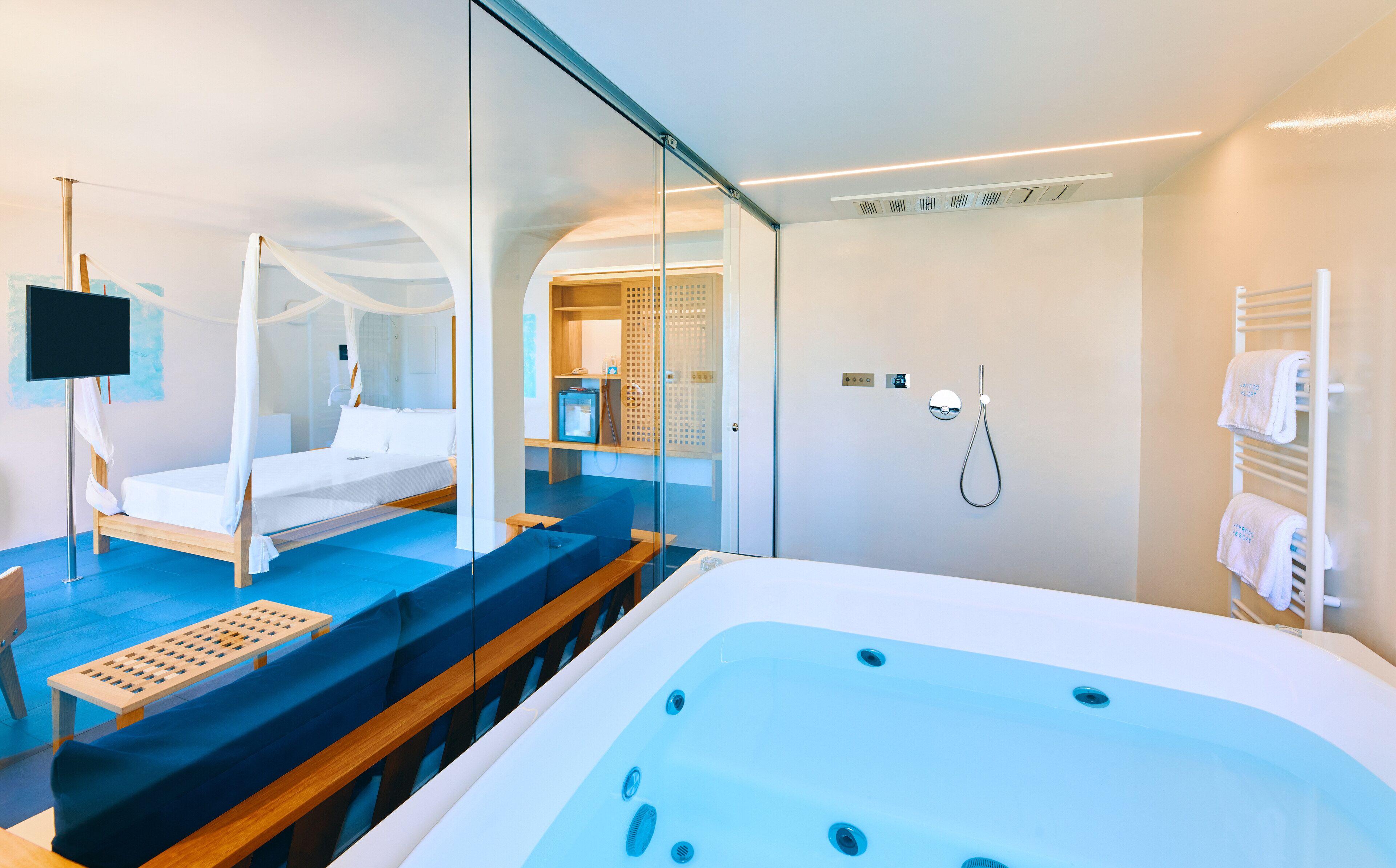 Une chambre d’hôtel moderne dotée d’une grande baignoire, d’un lit à baldaquin et d’une paroi en verre.