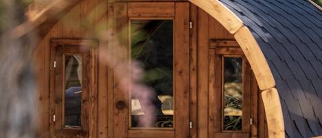 A wooden cabin with a curved roof, a small porch, and a window.