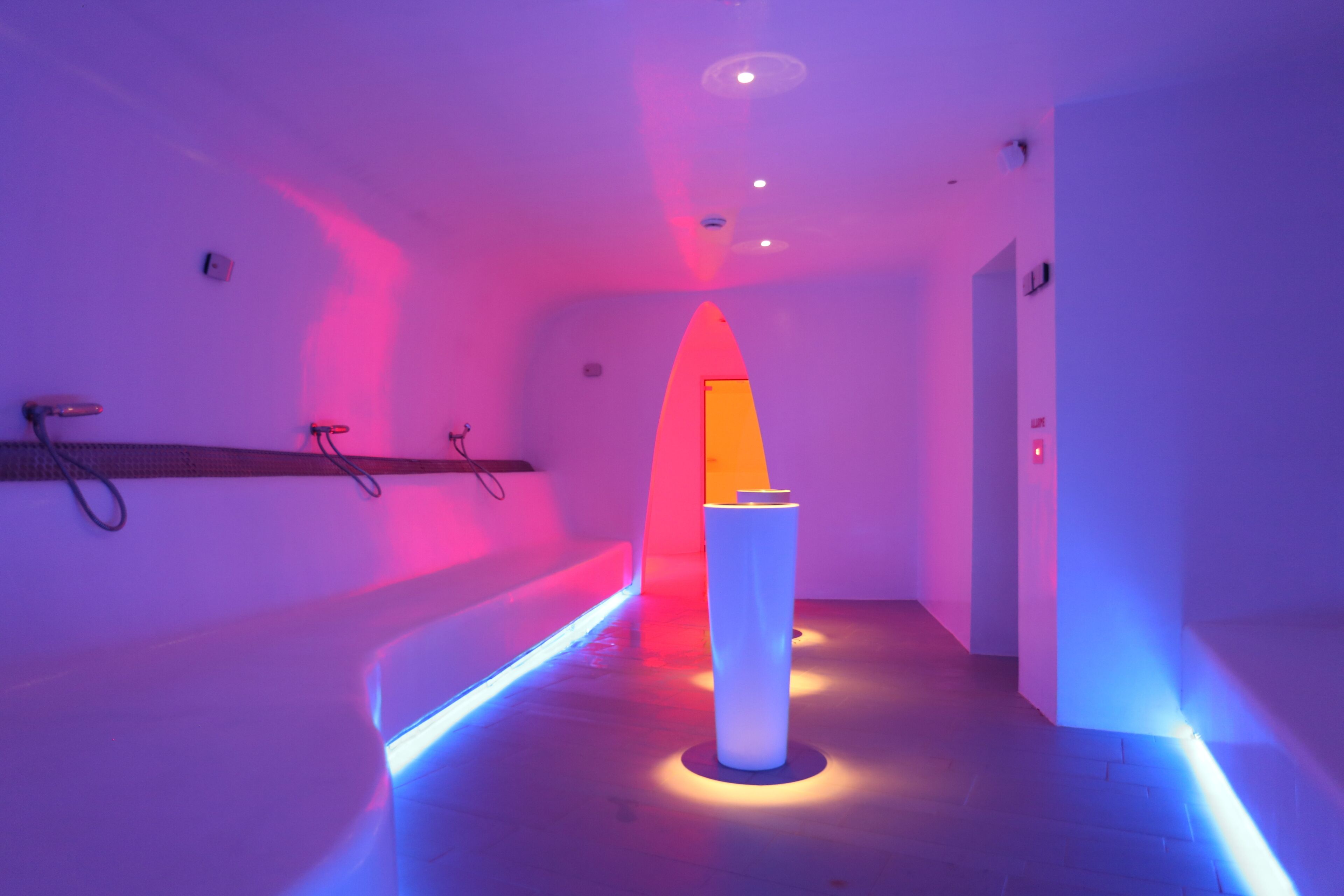 A modern interior with a central white pillar, ambient lighting, and a wall-mounted shelf.