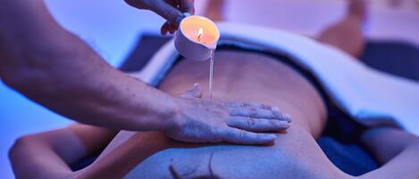 A person receiving a massage with a lit candle on their back.
