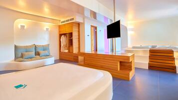 Una habitación de hotel moderna con una cama grande, un banco de madera, un televisor y un baño con bañera y ducha.