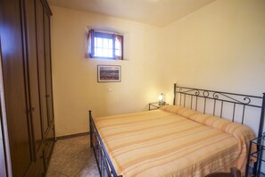 Un dormitorio con cama, ventana, mesita de noche y armario.