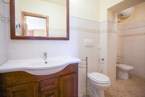 Un baño con lavamanos, espejo, inodoro y bidé.