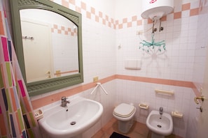 A bathroom with a sink, toilet, bidet, and mirror. - Appartamento Mono Serenella (Portoferraio)