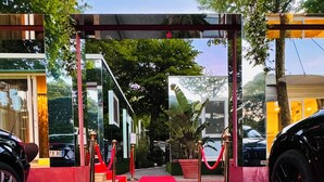 A red carpet event with a red carpet leading to a building entrance, surrounded by potted plants and parked cars. - Luxury Camp at Union Lido (Cavallino-Treporti)