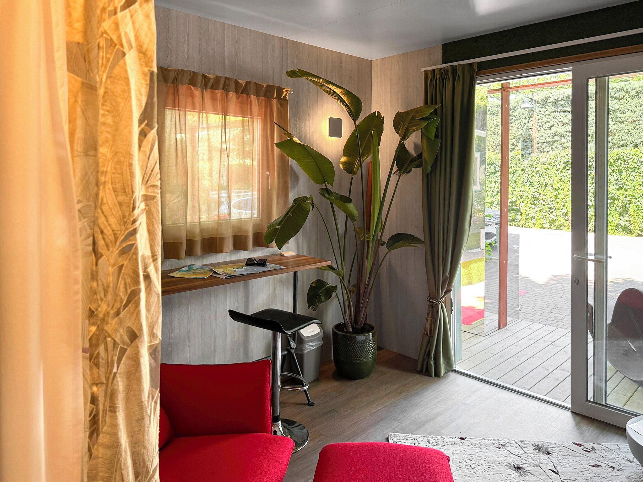 Un salon moderne avec un canapé rouge, une petite table et une grande plante.