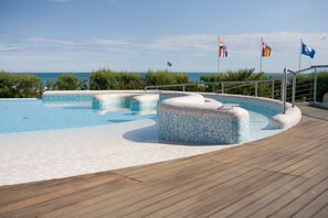 Ein Schwimmbecken mit Holzterrasse und Meerblick.